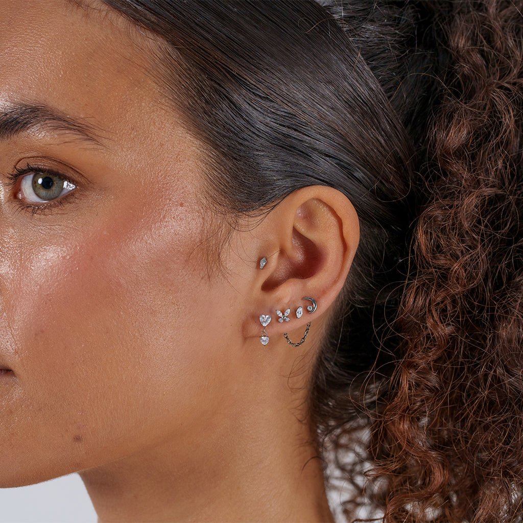 Gold-tone titanium single chain connector linking two ear piercings.