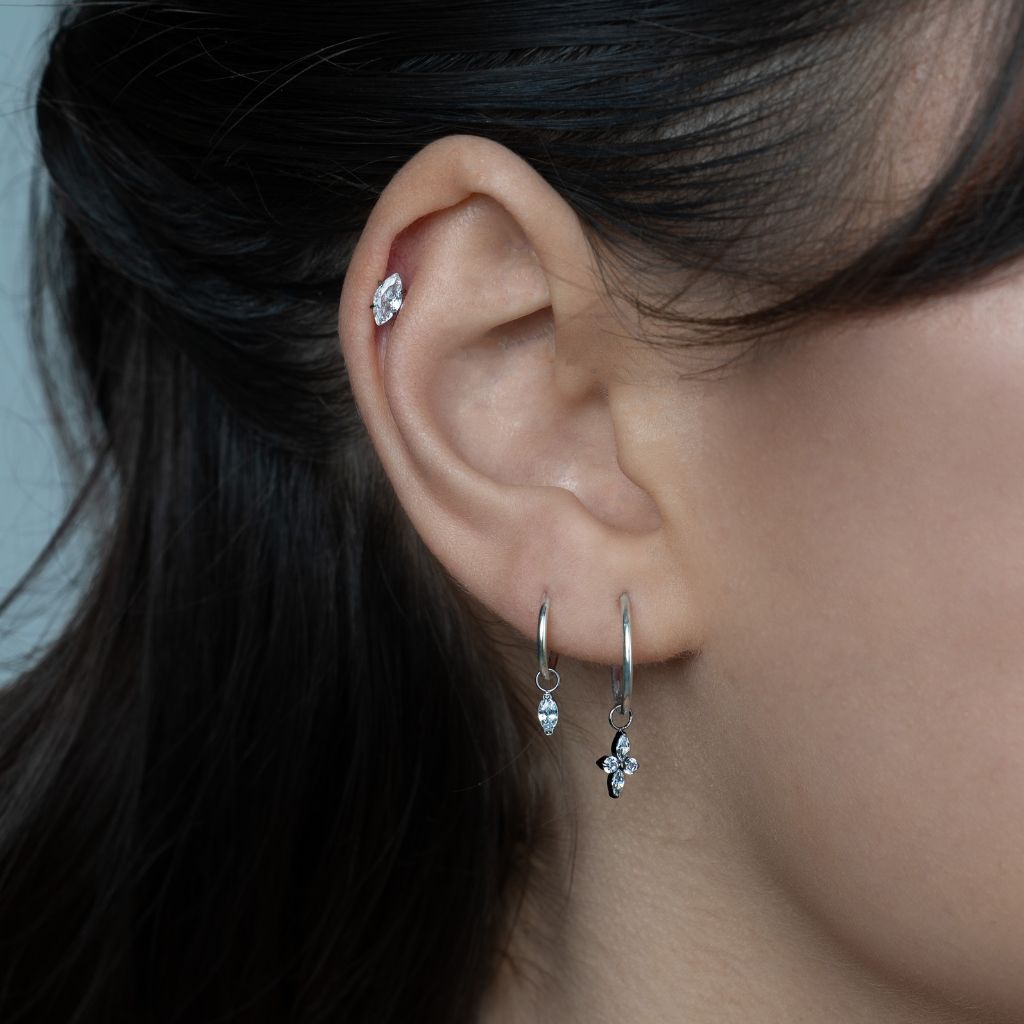 Silver-tone titanium four-point star cubic zirconia charm hanging from a hoop earring.