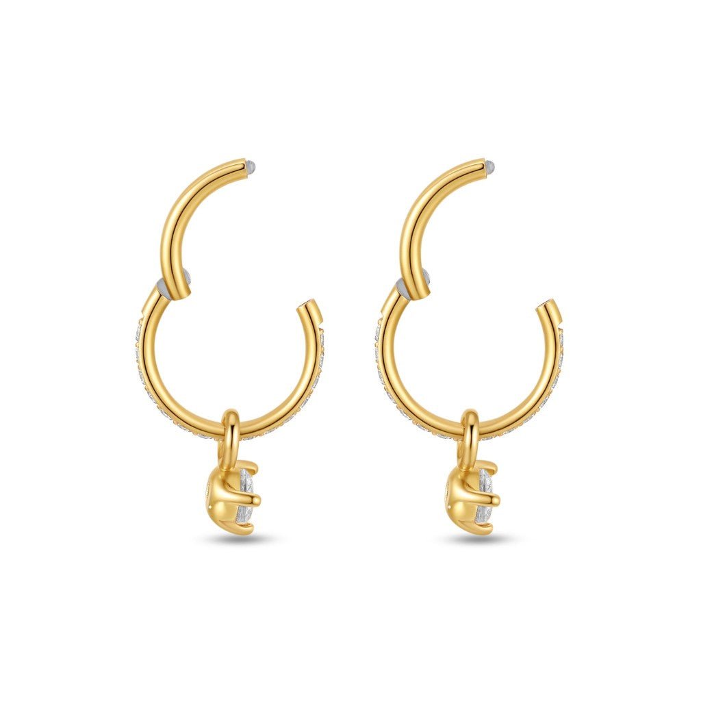 Pair of gold-tone surgical steel segment rings with hinged closure, micro pavé cubic zirconia detailing along the hoop, and round clear cubic zirconia dangle charms.