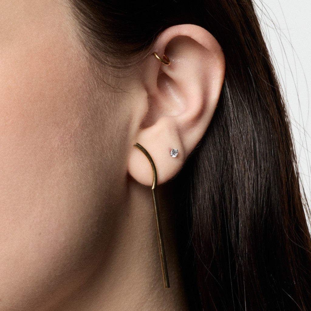 Close-up of model wearing gold long bar stud earrings
