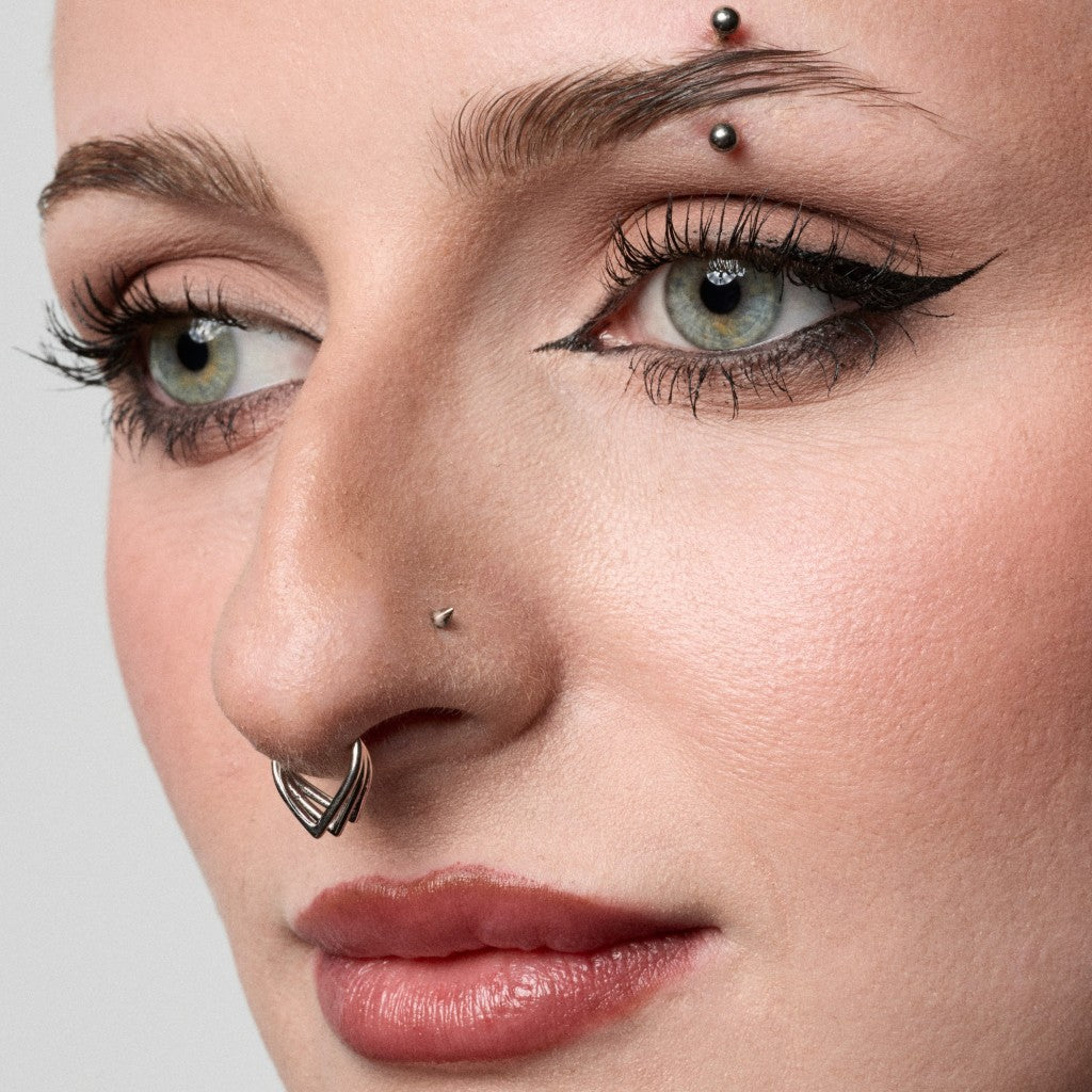 Close-up of model wearing a silver triple V-shaped segment ring septum piercing
