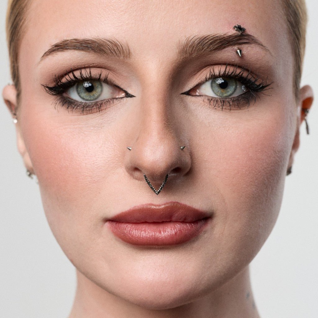 Close-up of model wearing a silver hammered V-shaped segment ring septum piercing
